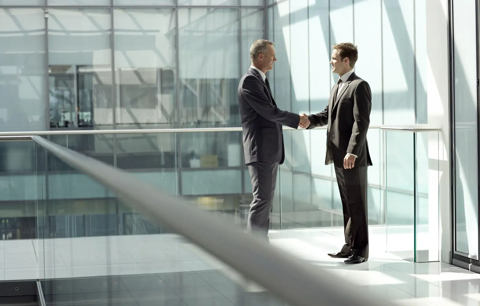 Two business people shaking hands in a glass-walled office